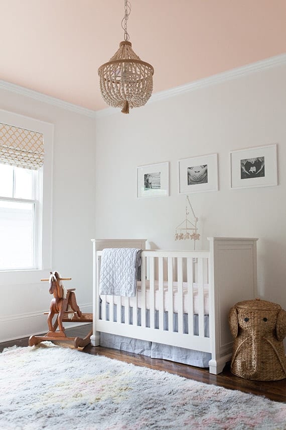 A nursery with white wall, a white crib and a blush ceiling.