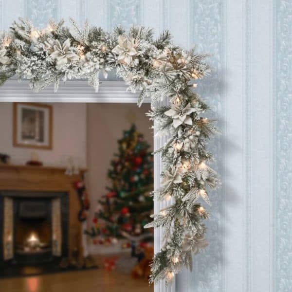 A flocked garland with white lights and small poinsettia flowers hung across a doorway.