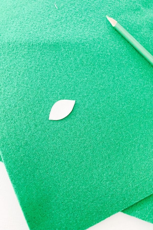 A piece of paper cut into the shape of a leaf and it is sitting on a piece of green felt.
