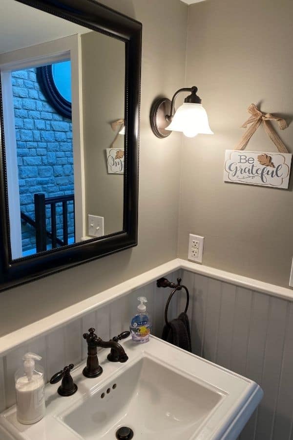 The before photo of my powder room with a be grateful sign hanging on the wall.