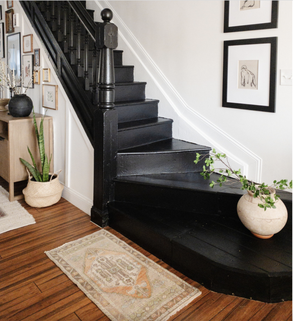 White walls, wood floors and black painted stairs.