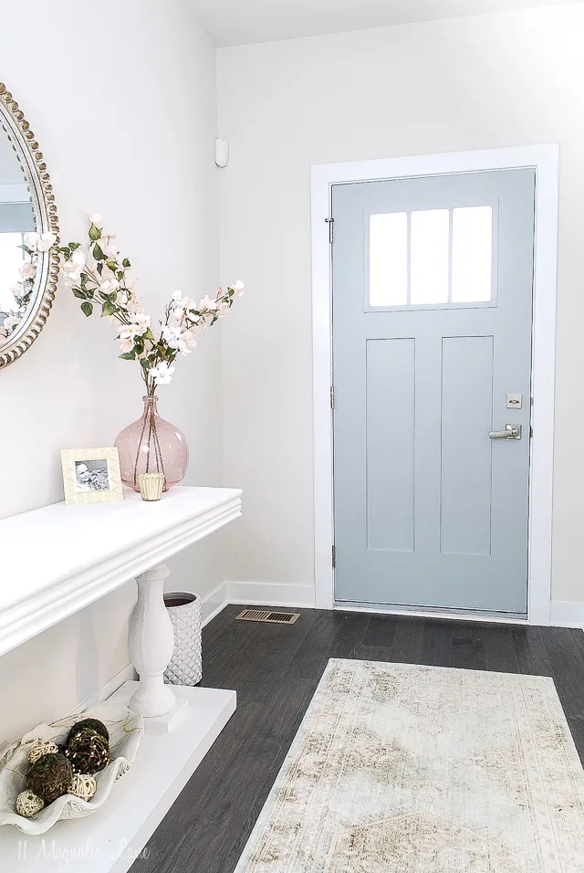 The entryway with Boothbay Gray on the inside of the door, dark wood floors, a white console table and a runner on the floor.