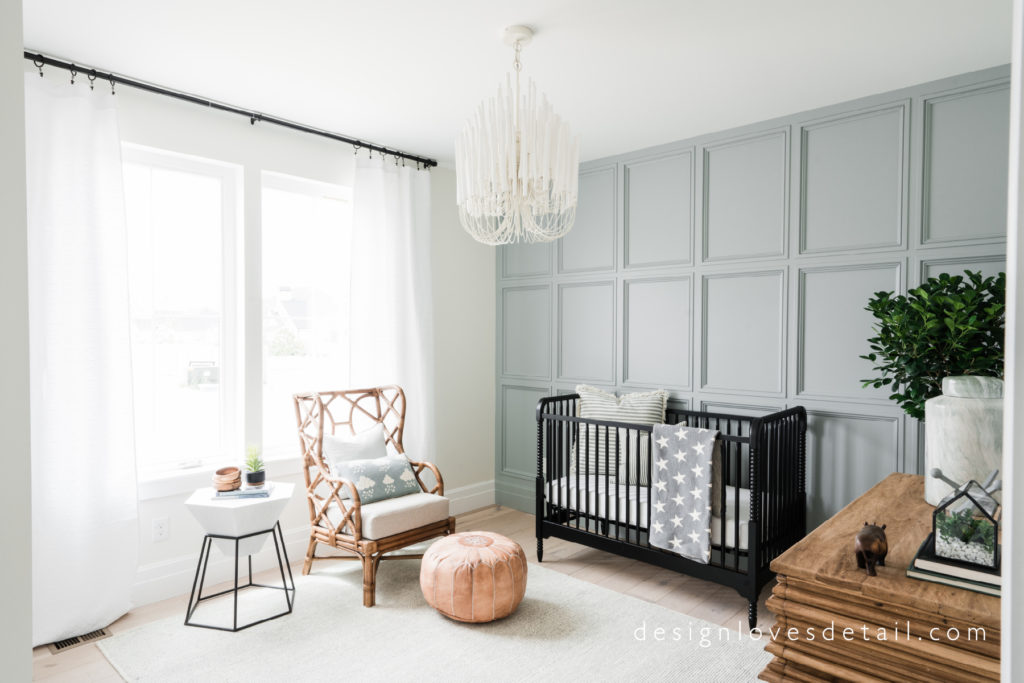A nursery with Boothbay Gray on an accent wall, a dark wood crib, light wood floors and white curtains on the window.