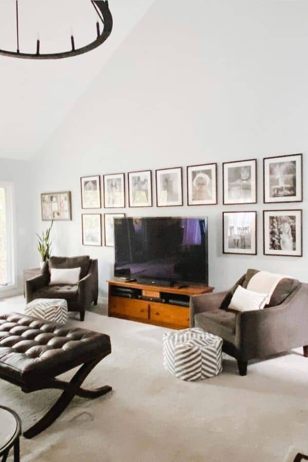 A family room with a gallery wall around a tv and a blanket on the back of a chair.