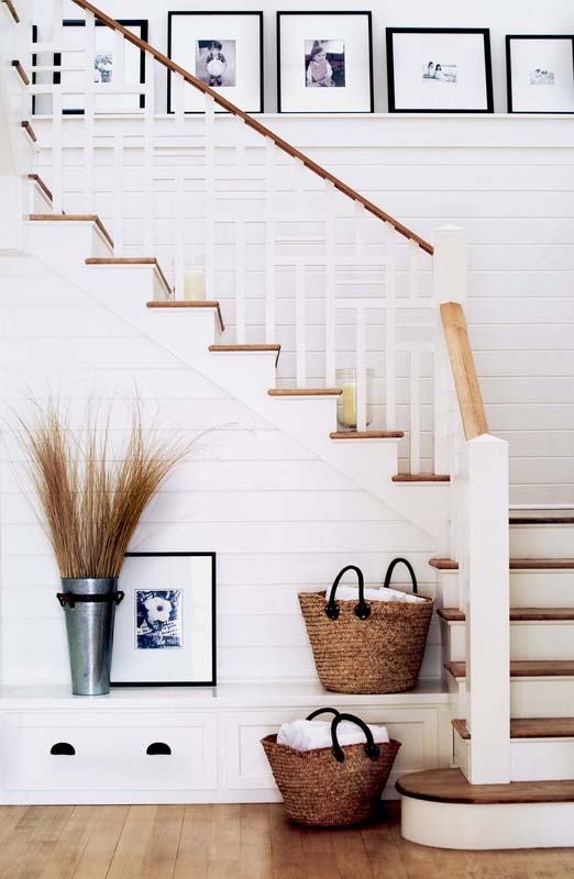 A staircase with shiplap walls painted white and a photo gallery.