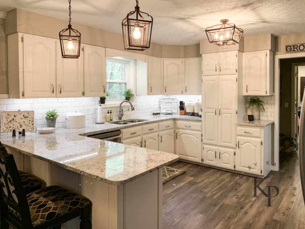 this kitchen is in a U shape with cabinets in Alabaster by Sherwin Williams and rustic pendents over the peninsula.