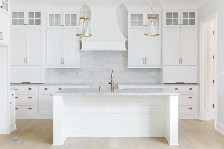 This kitchen has white cabinets in Sherwin Williams Pure white, gold hard ware and a marble subway tile backsplash.