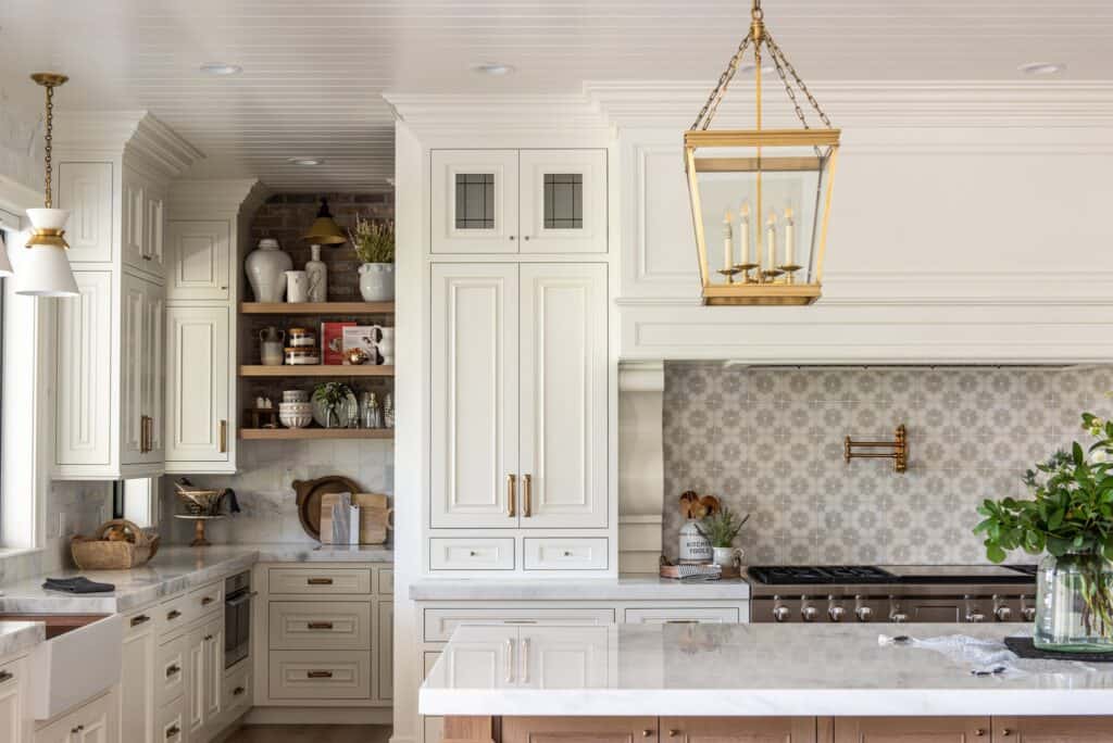 This kitchen has White Dove painted cabinetry, a gold lantern pendent over the island and a white pendent over the sink.
