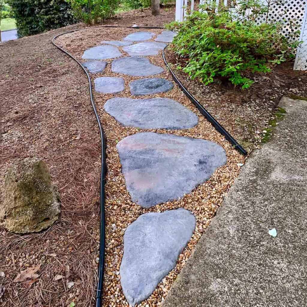 A stone path made of concrete through a yard.
