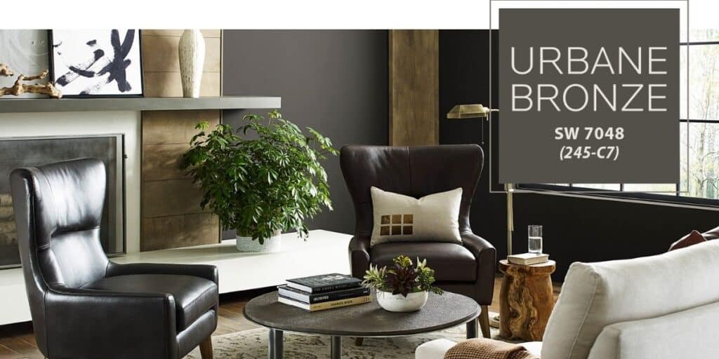 Urban Bronze, color of the year, used on walls in a lving room with light wood tones and dark leather chairs.