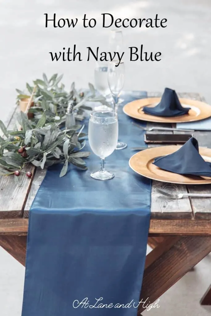 A dining table with a blue runner, gold plates and blue napkins.