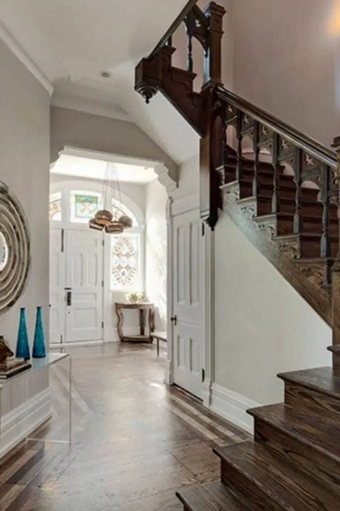 An entryway with Balboa Mist on the walls and a dark wood rustic staircase.