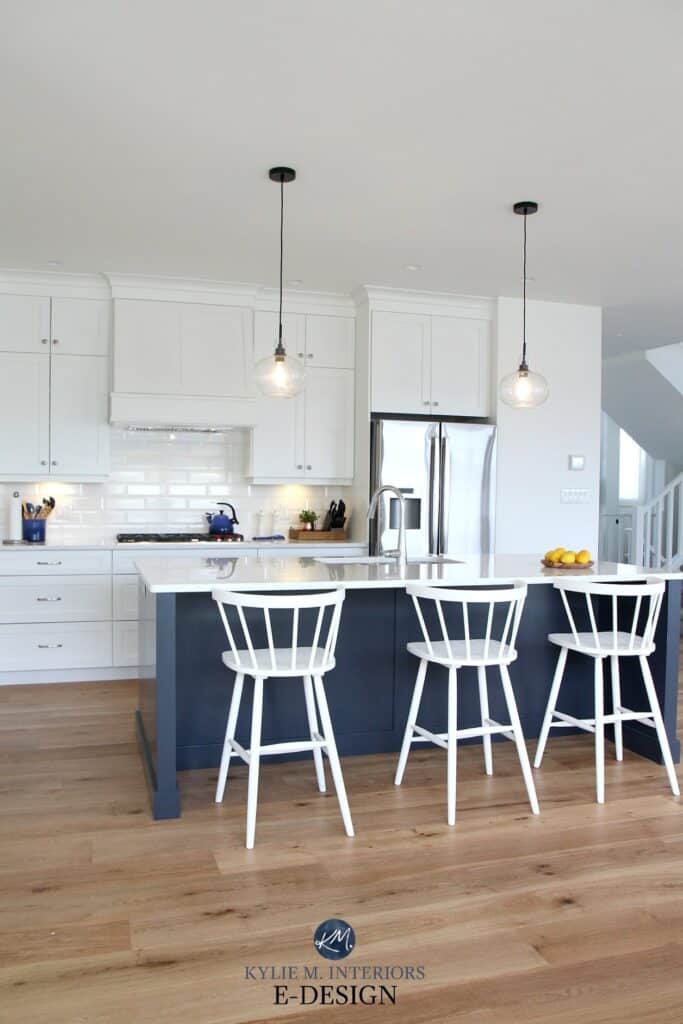 Cloud White used on the walls and cabinets in a different sheen in this all white kitchen with a navy blue island.