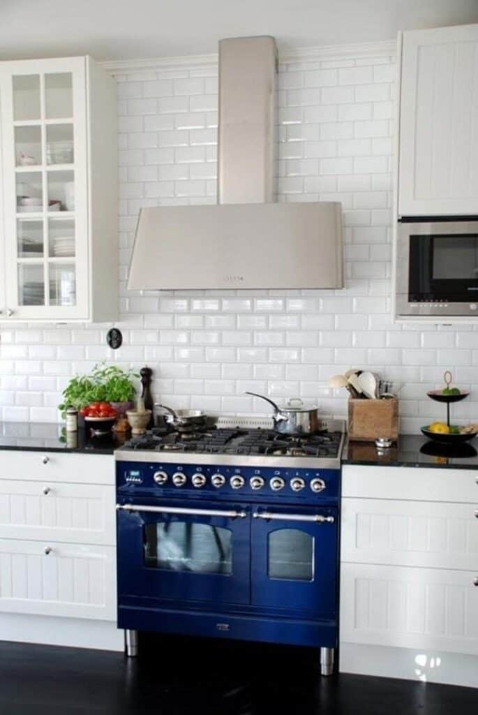 A white kitchen with a navy blue stove and black countertops.