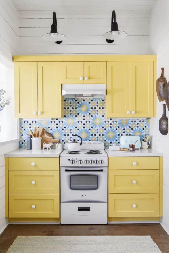 yellow cabinets, blue and white backsplash, white stove and shiplap walls.