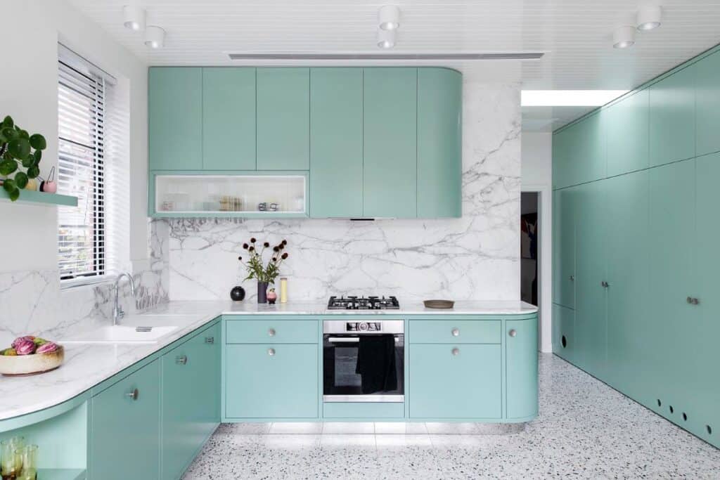 mint green cabinets with a marble counter and backsplash with terazzo floors.