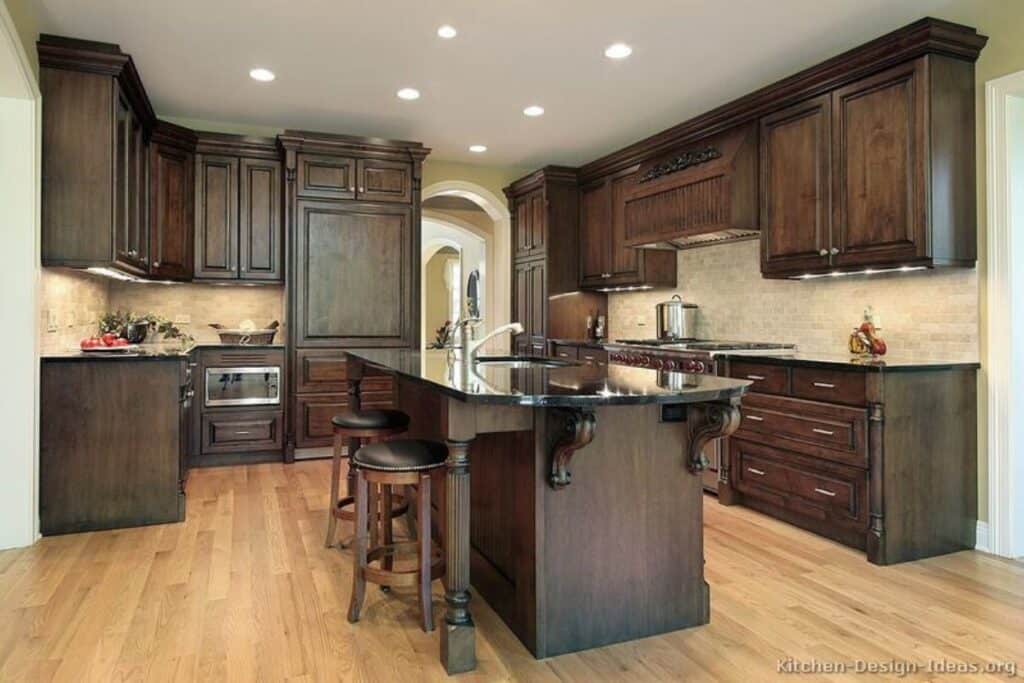 dark wood cabinets with black counters and light hardwood floors.