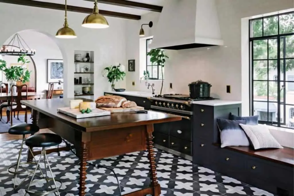 Black cabinets, white tile on the walls and a wood island on a patterned floor tile.