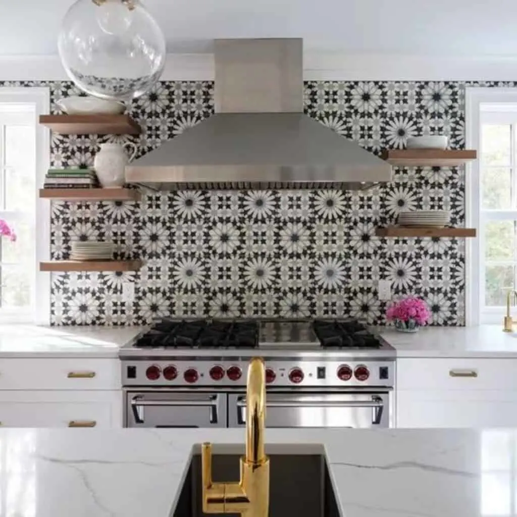Gray and white patterned tile behind a large stove, vent hood and four floating shelves.