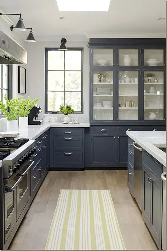 Black cabinets with a white counter and light hardwood floors with a green and white striped runner on it.