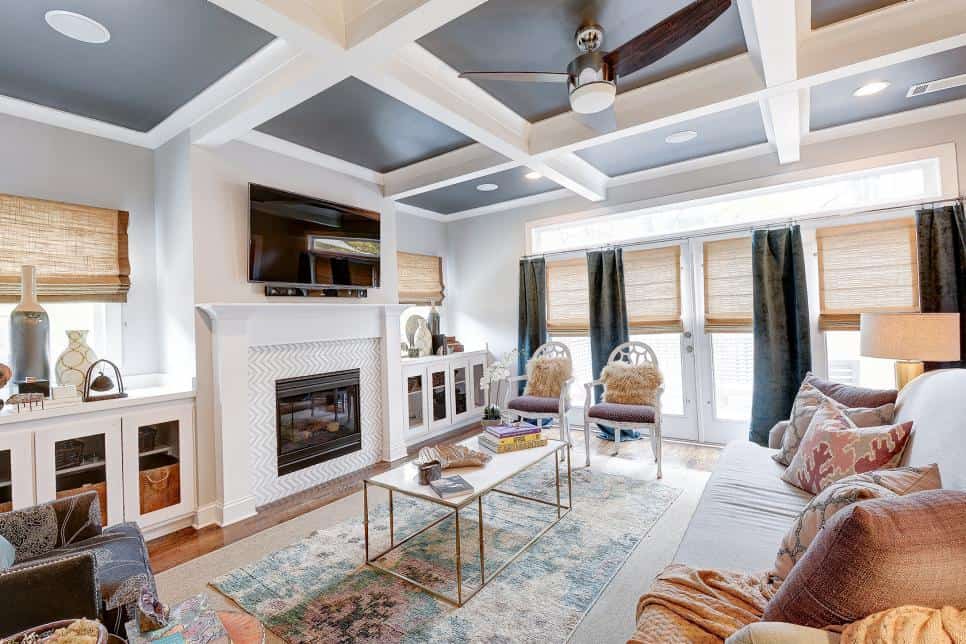 White walls and whit4e coffered ceiling with dark gray ceiling panels an da ceiling fan in the center.