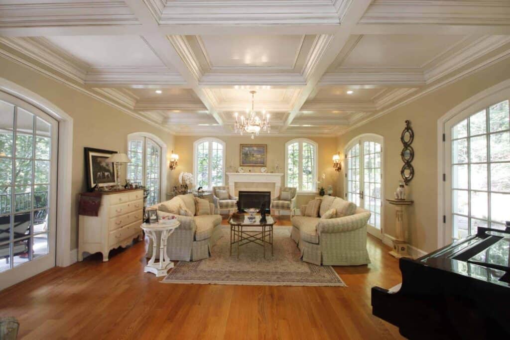 Yellow walls with very traditional furniture, a coffered ceiling in white and a baby grand piano.