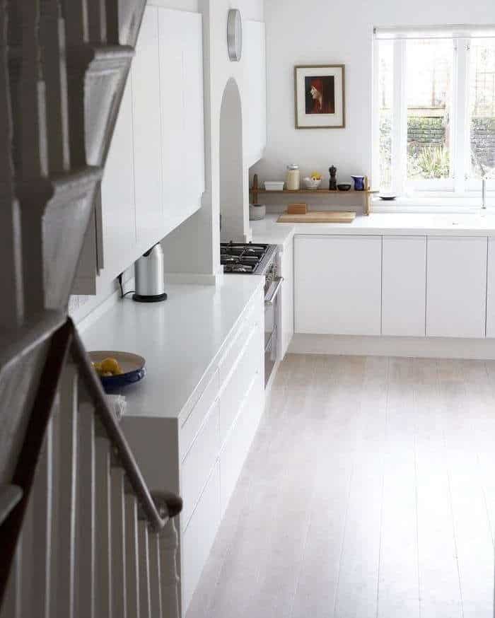 Light wood floors with white cabinets and white counters with lots of tall windows.