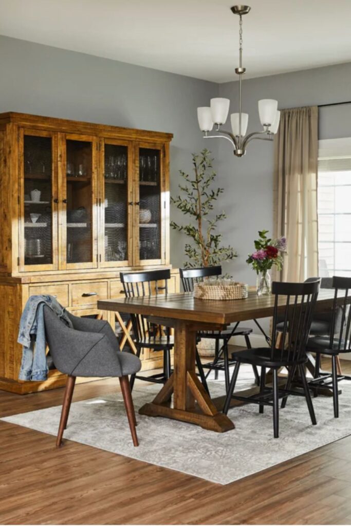 A dining room with a dark wood table and black windsor chairs.