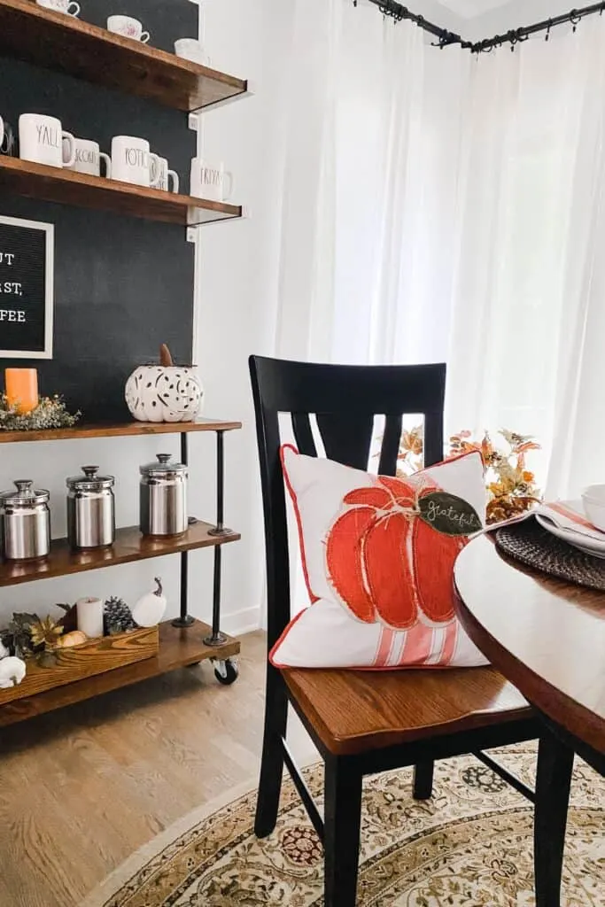 A chair with a pumpkin pillow on it.