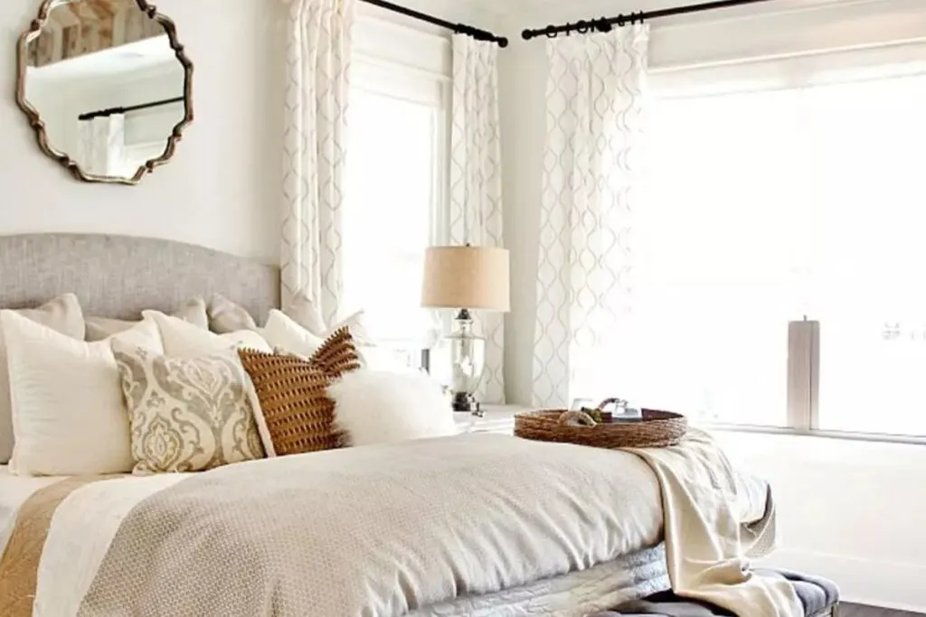 A bedroom with neutral linens and Greek Villa on the walls.