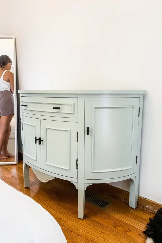 The finished cabinet painted sage green with black hardware.