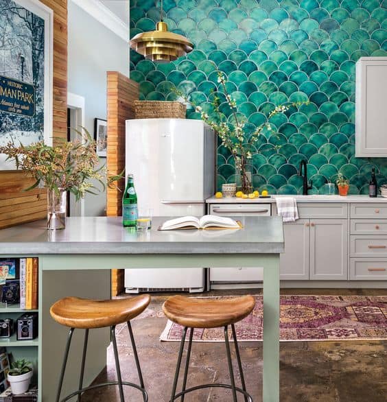 Teal scalloped tile in a kitchen with white appliances, off white cabinets and gold hardware.