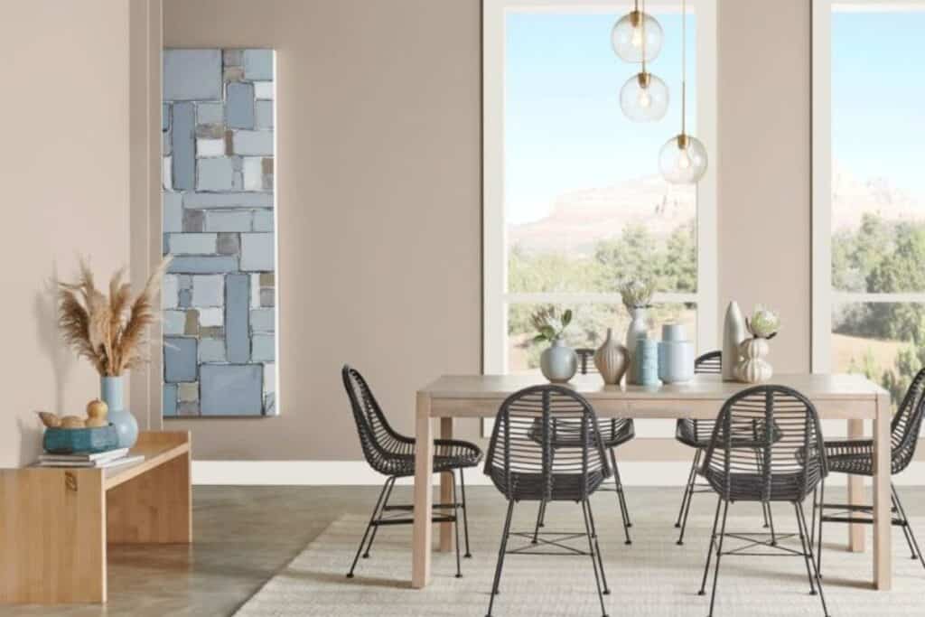 A dining room with tall windows, black chairs and stained concrete floors.