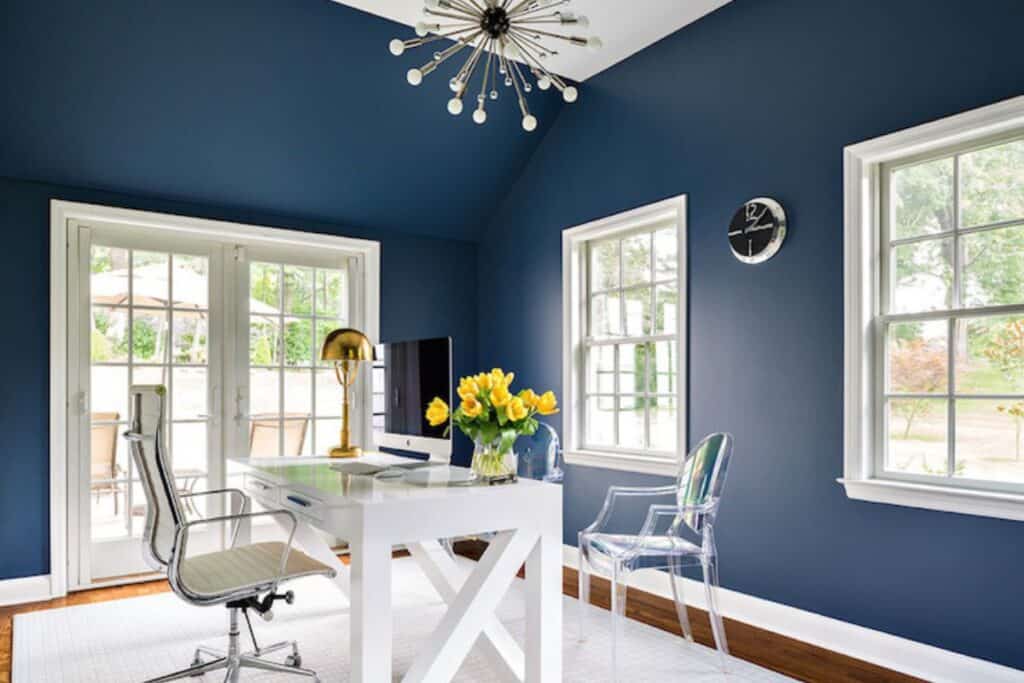 An office with Van deusen blue on the walls, white trim, white desk, white carpet, and medium brown hardwood floors.