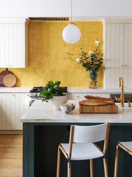 white cabinets with a bright yellow square tile backsplash and dark green island.