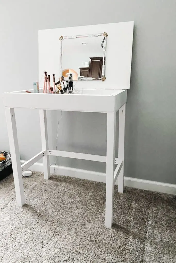 The finished vanity painted white with makeup tools inside.