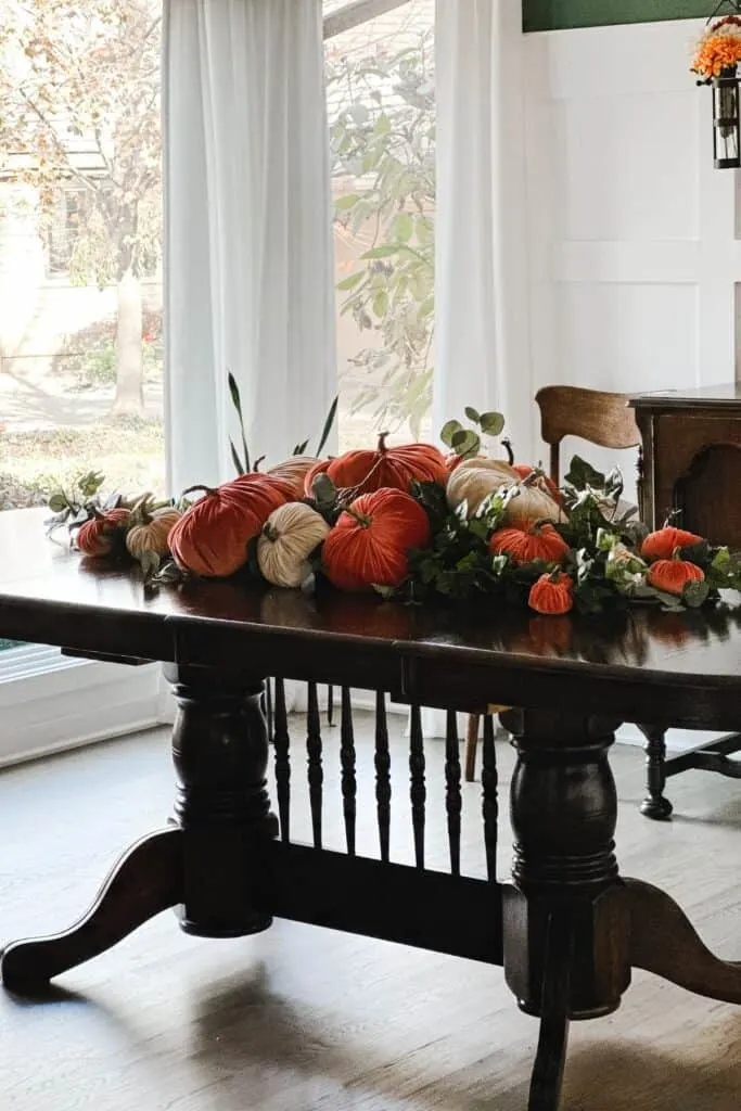 A view of my dark table with rust and champagne colored velvet pumpkins with greenery.