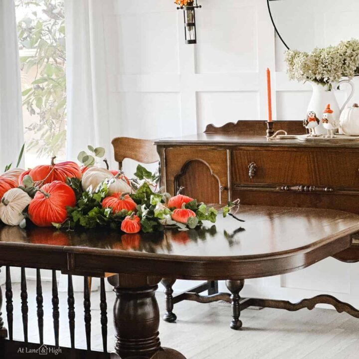 The dining room with the table full of rust and champagne colored velvet pumpkins with greenery.