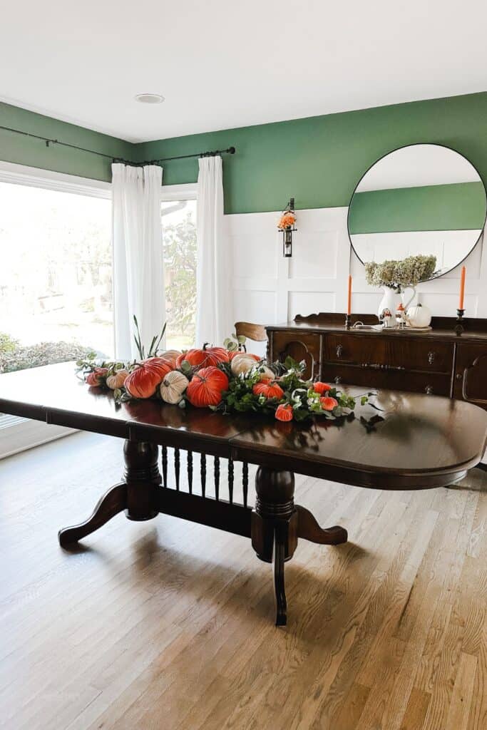 A wide view of my dining room with a dark stained table and buffet with all my velvet pumpkins on top with greenery.