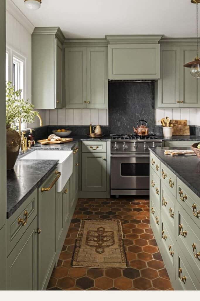A kitchen with Oil Cloth on the cabinets with gold hardare, black countertops and terra cotta floors in hexagon shape.