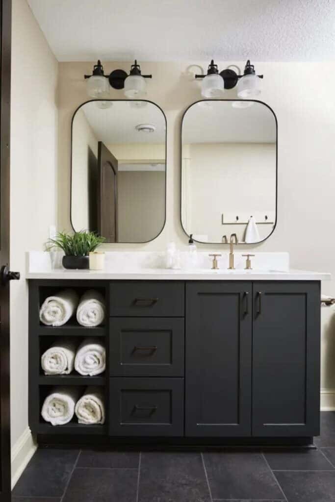 A bathroom with white walls and a vanity painted Iron Ore with a white countertop and two mirrors above.