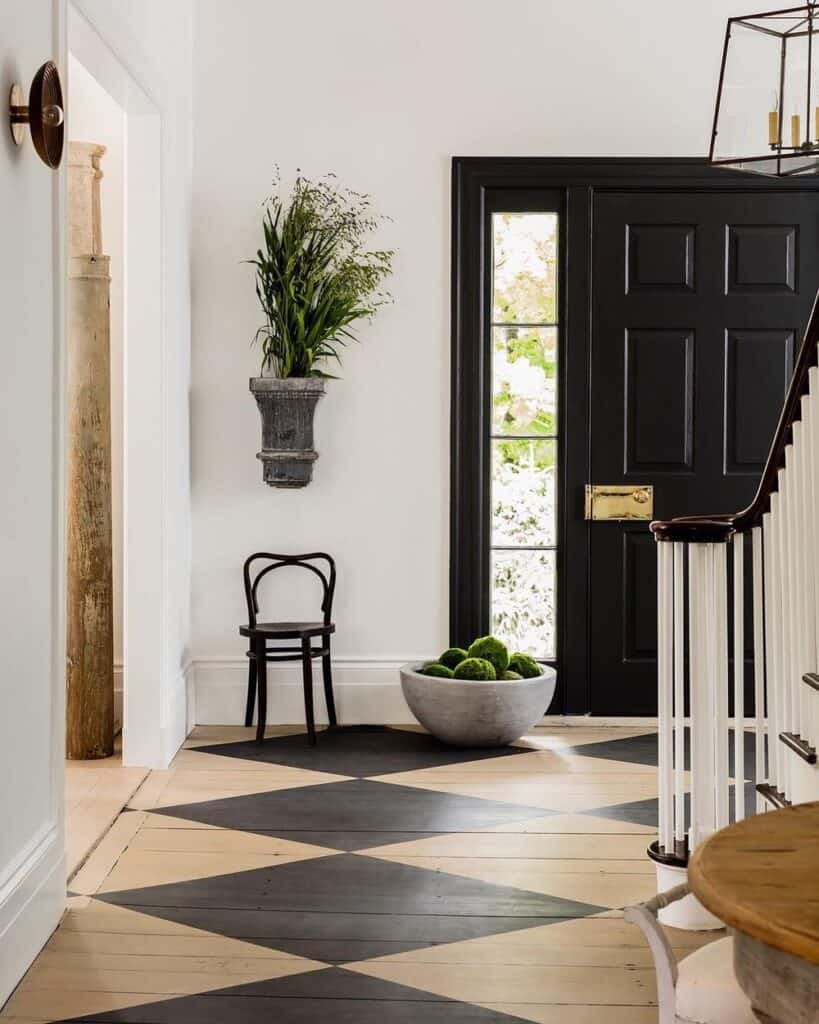 An entryway with black and brown painted checkererd floors, a front door painted black and white walls.
