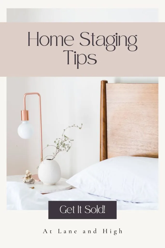 A bedroom with a wood headboard, white bedding, a nightstand with a marble round top and a white vase.