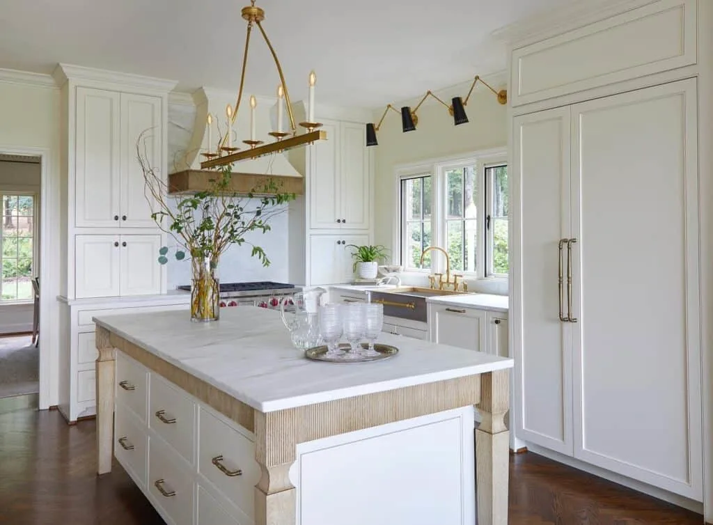 A kitchen with Linen White on all the cabinetry and walls, gold and black light fixtures and gold hardware on the sink and cabinets.