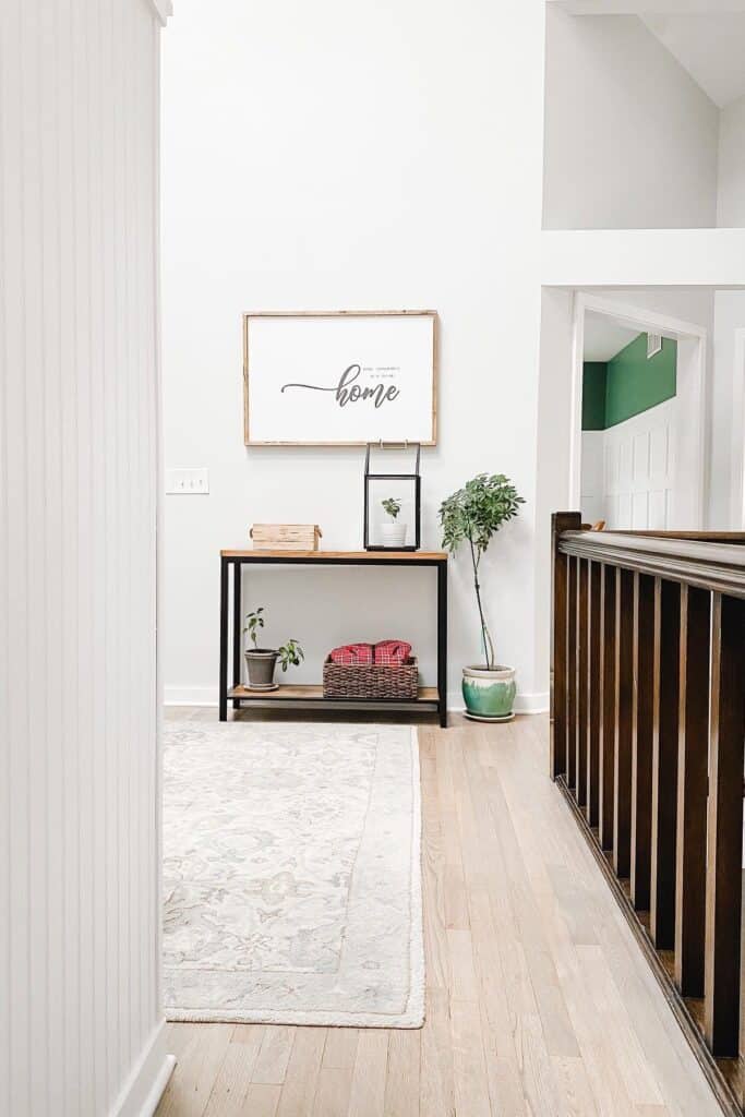 A hallway with a console table at the end with a sign above that says 