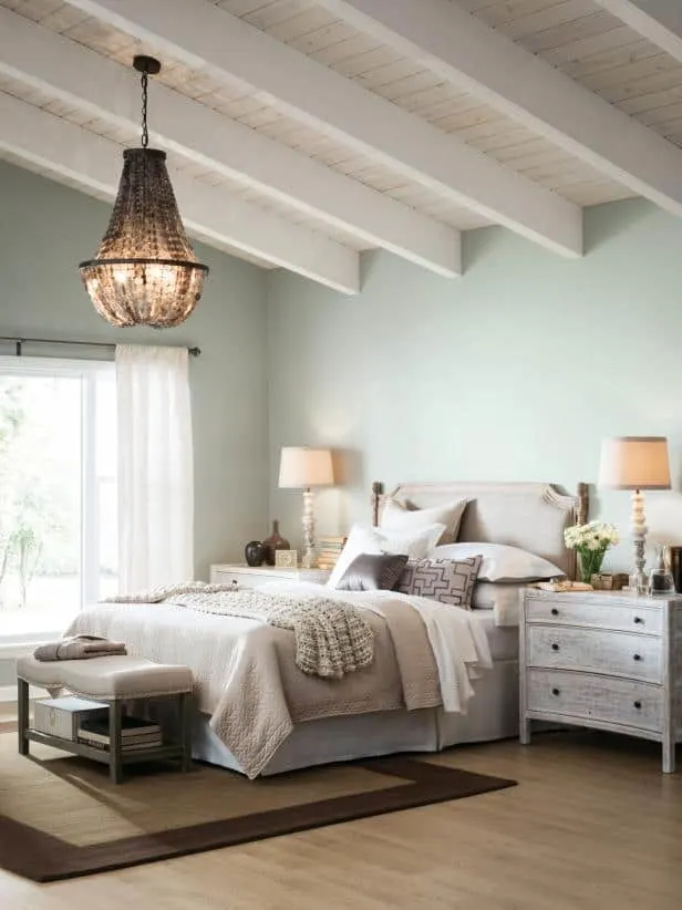 A bedroom with Silver Strand on the walls and exposed beams on the ceiling painted white.