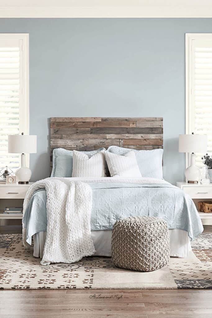 A bedroom with Krypton on the walls, a rustic wood headboard, white bedside tables and white lamps.