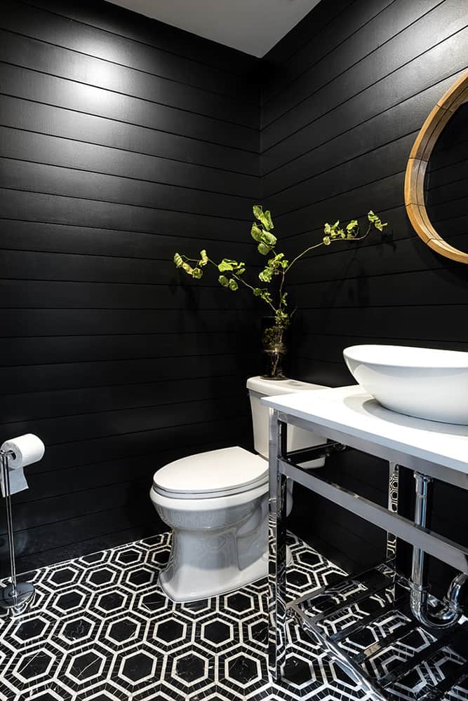 Shiplap in a bathroom that has been painted black with a black and white tile on the floor.