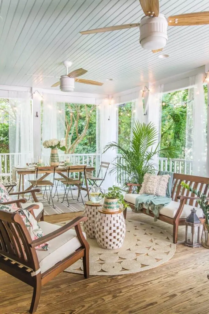 A screened in porch with a dining table and chairs and a couch and two arm chairs.