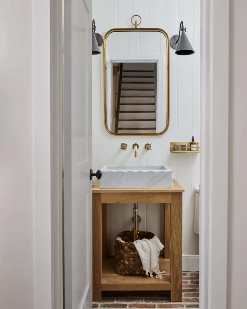 White vertical shiplap and brick floors in a bathroom with gold accents.